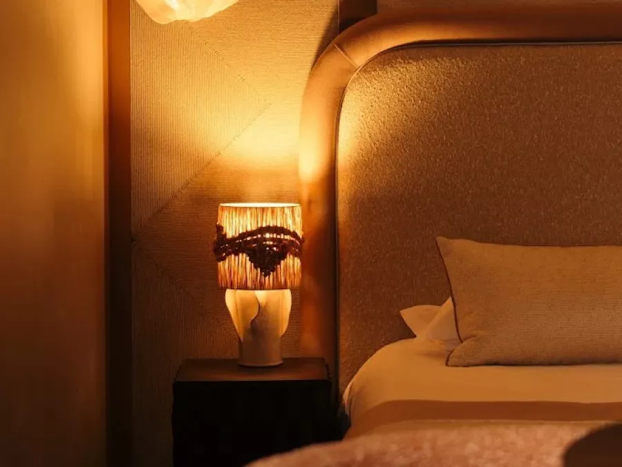 Tête de lit capitonnée en bouclé et applique en albâtre, une chambre pensée comme un cocon